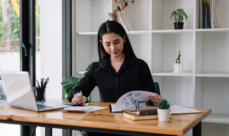 Female Businesswoman working on laptop computer doing finances,accounting analysis,report,data and pointing graph at the office.