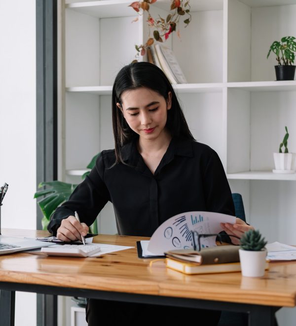 Female Businesswoman working on laptop computer doing finances,accounting analysis,report,data and pointing graph at the office.